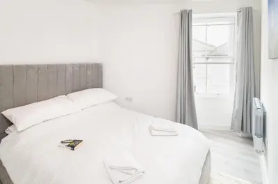 a white bed in a room with a window at Trehawke House in Liskeard