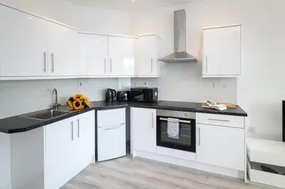 a kitchen with white cabinets and a black counter top at Trehawke House in Liskeard
