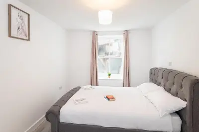a bedroom with a bed with white sheets and a window at Trehawke House in Liskeard
