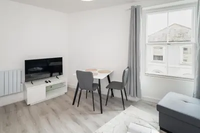 a living room with a table and chairs and a tv at Trehawke House in Liskeard