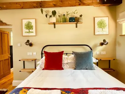 a bedroom with a bed with red and blue pillows at The Dairy - Luxurious Hideaway on The Lizard in Cury