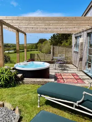 a backyard with a hot tub and a wooden pergola at The Dairy - Luxurious Hideaway on The Lizard in Cury