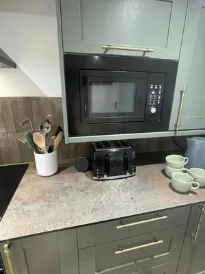 a kitchen with a microwave and a counter with utensils at Bagnalls Cottage, A newly renovated cottage in the heart of the Downalong, St Ives moments from the harbour beach in St Ives