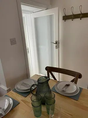a wooden table with plates and a pitcher on it at Bagnalls Cottage, A newly renovated cottage in the heart of the Downalong, St Ives moments from the harbour beach in St Ives