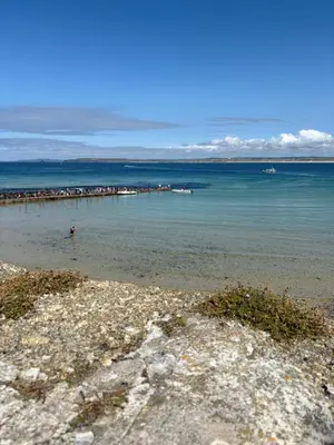 a beach with a pier in the water at Bagnalls Cottage, A newly renovated cottage in the heart of the Downalong, St Ives moments from the harbour beach in St Ives