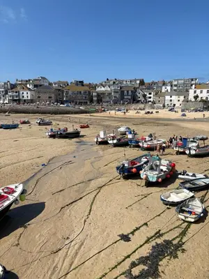 a group of boats sitting on the sand on a beach at Bagnalls Cottage, A newly renovated cottage in the heart of the Downalong, St Ives moments from the harbour beach in St Ives