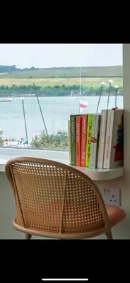a chair in front of a shelf with books at 3 Bed Stylish Beachfront Retreat in Roche