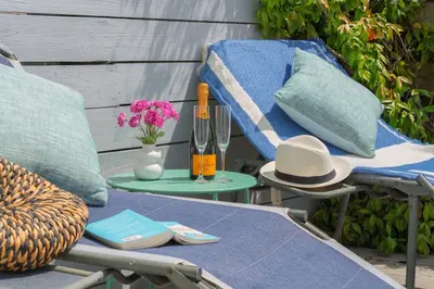 a table with a hat and a table with a chair at 3 Bed Stylish Beachfront Retreat in Roche