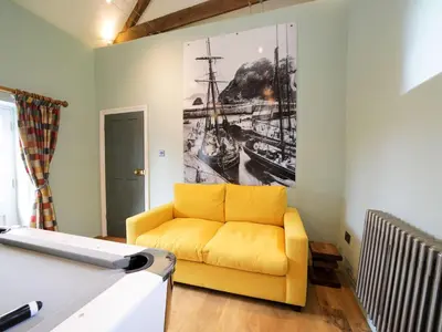 a yellow couch in a living room with a painting on the wall at Polmear Farm House in Charlestown