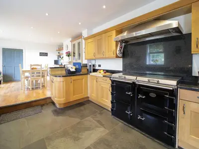 a kitchen with wooden cabinets and a black stove top oven at Polmear Farm House in Charlestown