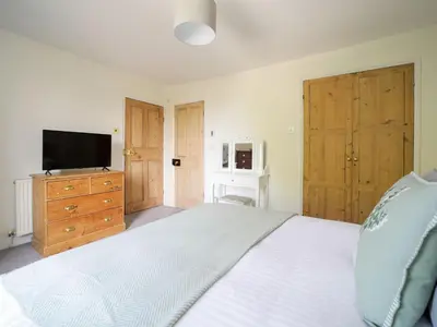 a bedroom with a white bed and a television at Polmear Farm House in Charlestown