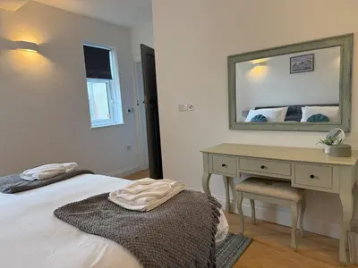 a bedroom with a bed and a desk with a mirror at Modern Town Centre Flat in St Austell