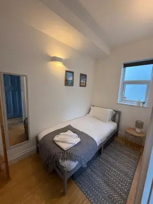 a small bedroom with a bed and a window at Modern Town Centre Flat in St Austell