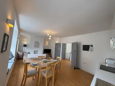a dining room and living room with a table and chairs at Modern Town Centre Flat in St Austell