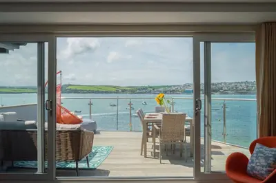 a balcony with a table and a view of the water at FERRYPOINT - 3 Bed Stylish Beachfront Retreat in Padstow