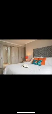 a bedroom with a large white bed with orange and blue pillows at FERRYPOINT - 3 Bed Stylish Beachfront Retreat in Padstow
