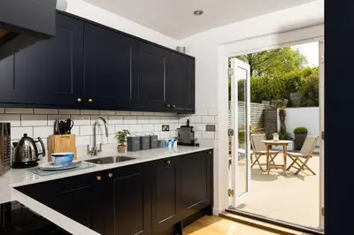 a kitchen with black cabinets and a sliding glass door at Bryn Cottage in Padstow