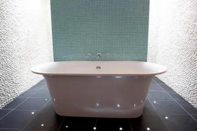a bath tub in a bathroom with a green wall at Bryn Cottage in Padstow