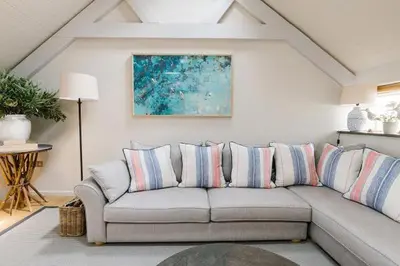 a living room with a gray couch with striped pillows at Bryn Cottage in Padstow