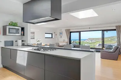 a kitchen with a stove top oven next to a living room at Finest Retreats - Tregarden in Bude