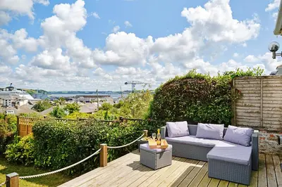 a patio with a couch on a wooden deck at Finest Retreats - Lansdowne in Falmouth