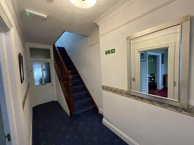 a hallway with a staircase and a large mirror at Pendrin Guest House in Tintagel