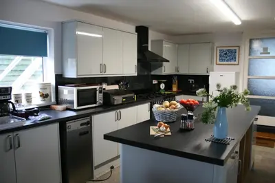 a kitchen with white cabinets and a black counter top at Pendrin Guest House in Tintagel