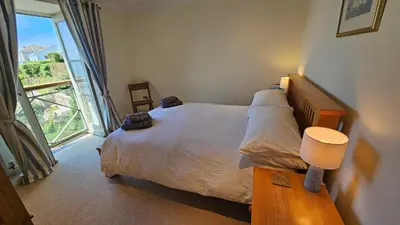 a bedroom with a bed and a large window at Crow's Nest in Saint Mawes