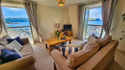a living room with couches and a view of the water at Crow's Nest in Saint Mawes