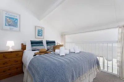 a bedroom with a bed with a blue blanket and a window at 15 Barnaloft in St Ives