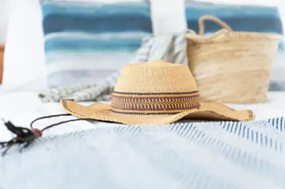 a straw hat sitting on a bed with a purse at 15 Barnaloft in St Ives