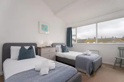 a bedroom with two beds and a large window at 17 Barnaloft in St Ives