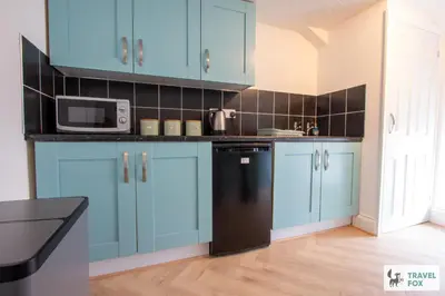 a kitchen with blue cabinets and a black refrigerator at The Bird's Nest - Free Parking! in Boscastle