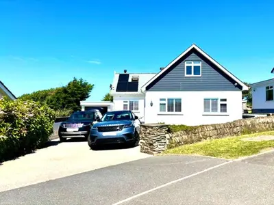two cars parked in front of a house at Porth Beach Lodge in Saint Columb Minor