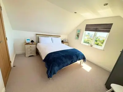 a bedroom with a large bed with a window at Porth Beach Lodge in Saint Columb Minor