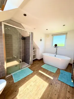 a bathroom with a tub and a shower and a sink at Porth Beach Lodge in Saint Columb Minor