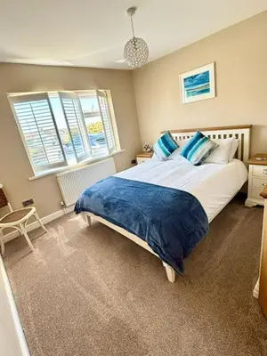 a bedroom with a large bed with blue pillows at Porth Beach Lodge in Saint Columb Minor