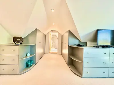 an attic room with a tv and a dresser at Porth Beach Lodge in Saint Columb Minor