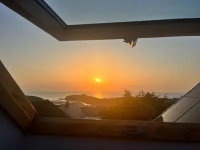 a view of the sunset from a window of a house at Porth Beach Lodge in Saint Columb Minor