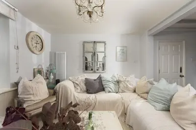 a living room with a white couch and a chandelier at Almond Cottage - Pets welcome - Free Parking - Garden in Hayle