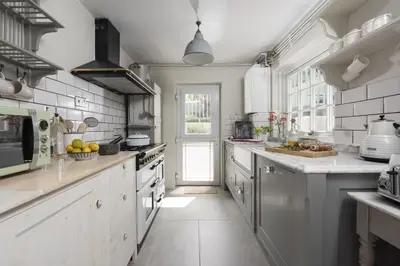 a large kitchen with white counters and a door at Almond Cottage - Pets welcome - Free Parking - Garden in Hayle