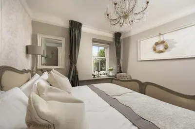 a bedroom with a white bed and a chandelier at Almond Cottage - Pets welcome - Free Parking - Garden in Hayle