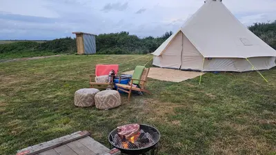 a tent and a chair and a fire in a field at Tiny Treamble in Cubert