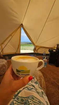 a person holding a cup of coffee in a tent at Tiny Treamble in Cubert