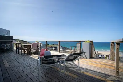 a deck with a table and chairs on the beach at Trewirgie in St Ives