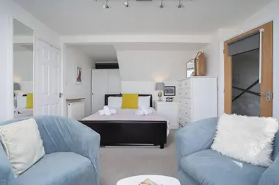 a bedroom with a bed and two blue chairs at Trewirgie in St Ives