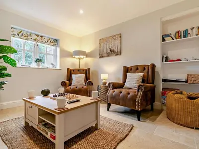 a living room with two chairs and a table at Rose Cottage in Saint Hilary
