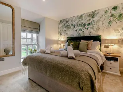 a bedroom with a large bed with a floral wall at Rose Cottage in Saint Hilary