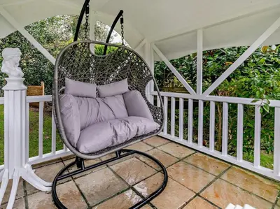 a porch swing with purple pillows in it at Rose Cottage in Saint Hilary
