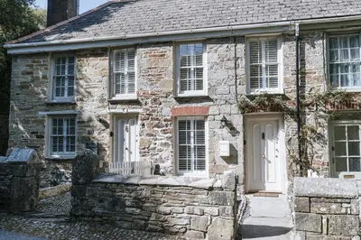 an old stone house with white doors and windows at Bluck's cottage in St. Agnes